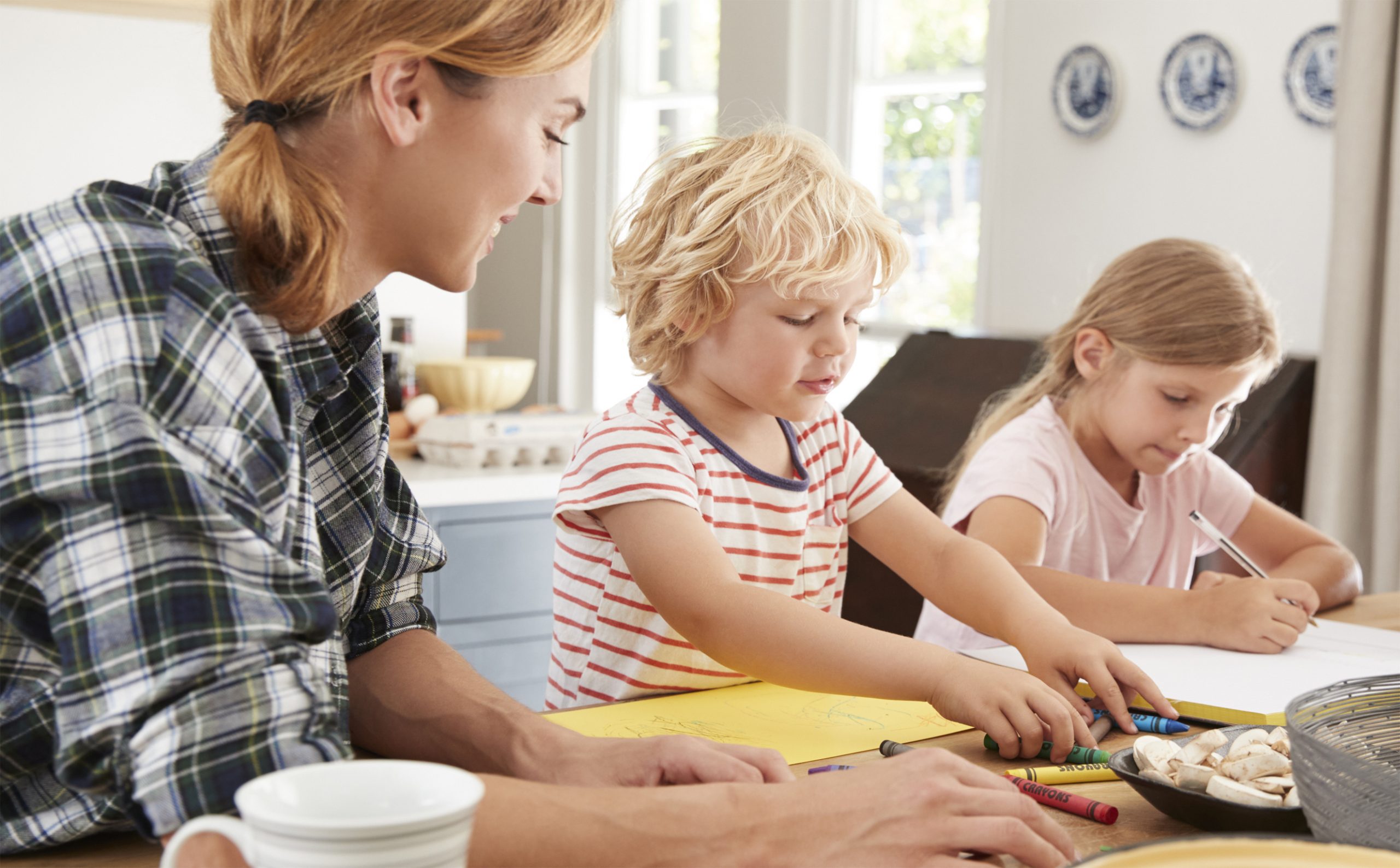 Mom helping young son and daughter with family tree project